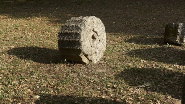 Round stone on earthy soil with surrounding shade, Archaeological Site, Ancient Olympia, Olympia, Peloponnese, Greece