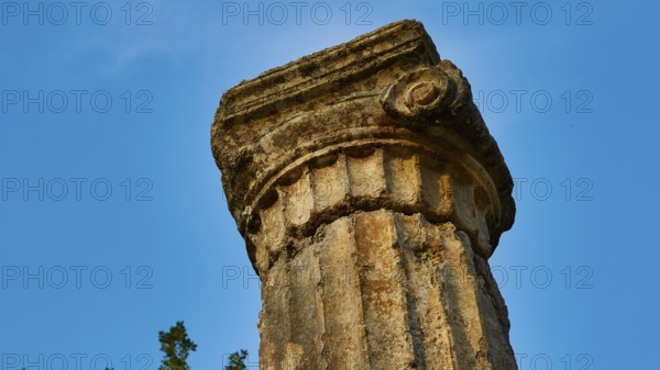 Pillar of Philippeion, head of an ancient stone column with decorated surface against a blue sky, Archaeological Site, Ancient Olympia, Olympia, Peloponnese, Greece