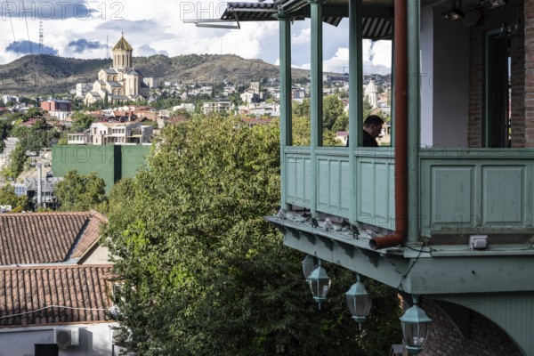 Tbilisi, Georgia. September 12th 2025 Traditional wooden balcony of a local Georgian house overlooking Tbilisi and the Holy Trinity Cathedral, Georgia