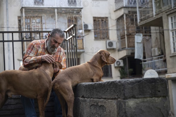 Tbilisi, Georgia. September 12th 2025. A local Georgian man with his pet dogs in the streets of Tbilisi Old Town, Georgia