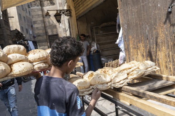 Cairo, Egypt. April 15th 2025. An Egyptian boy delivers baked traditional Baladi flat bread to a shop from a local bakery in Cairo, Egypt
