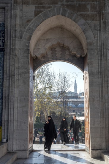 Istanbul, Turkey. January 3rd 2025. Muslim women entering the arched door at the entrance to newly restored Yeni Camii or New Mosque in the Eminonu district of Fatih, Istanbul, Turkey