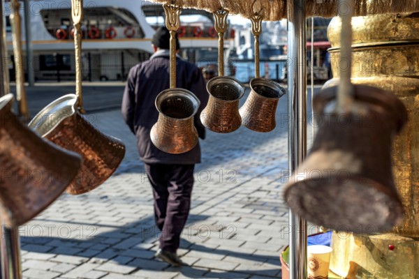 Traditional Turkish copper coffee pots hanging from a street stall beside the Karakoy ferry port, Istanbul, Turkey