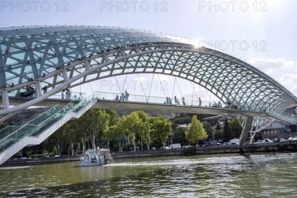 Tbilisi, Georgia. August 26th 2025. Tourists cross The Bridge of Peace over the Kura River also known in Georgia as the Mtkvari River in the Georgian capital, Tbilisi, Georgia