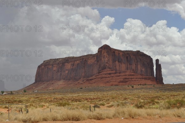 Huge rock in a wide desert landscape with cloudy sky in the background, Monument Valley, Navajo Tribal Park, Navajo Nation Reservation, Utah, Arizona, USA