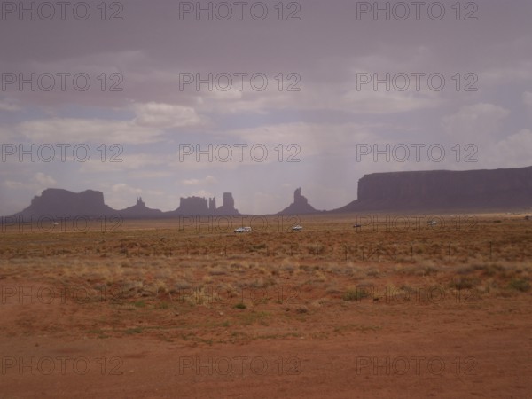 Wide, flat desert landscape with scattered rock formations and cloudy sky, Monument Valley, Navajo Tribal Park, Navajo Nation Reservation, Utah, Arizona, USA