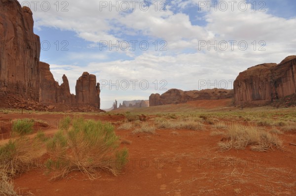 Wide valley with high rock walls surrounded by dry, red landscape, Monument Valley, Navajo Tribal Park, Navajo Nation Reservation, Utah, Arizona, USA