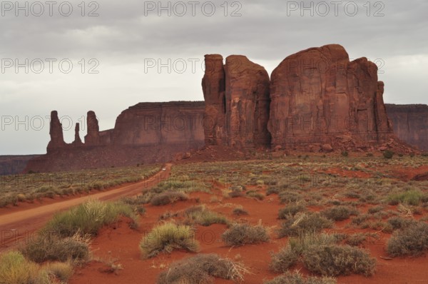 Majestic sandstone cliffs rise in a vast desert landscape under cloudy skies after a heavy thunderstorm. Monument Valley, Navajo Tribal Park, Navajo Nation Reservation, Utah, Arizona, United States of America