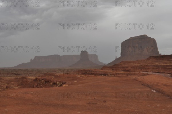 Impressive mesas under a cloudy sky in a vast desert landscape after a severe thunderstorm, Monument Valley, Navajo Tribal Park, Navajo Nation Reservation, Utah, Arizona, USA