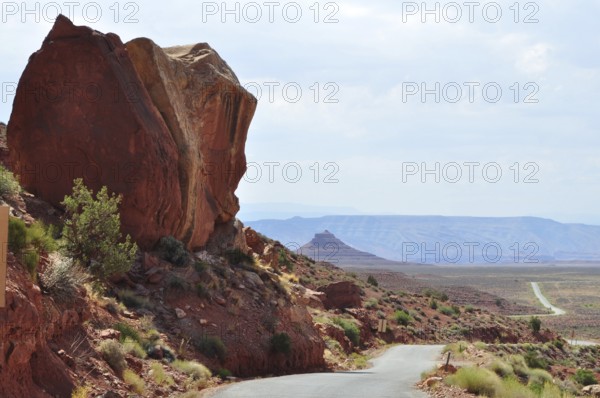 Large rock juts out next to a road in a vast desert landscape, Monument Valley, Navajo Tribal Park, Navajo Nation Reservation, Utah, Arizona, USA