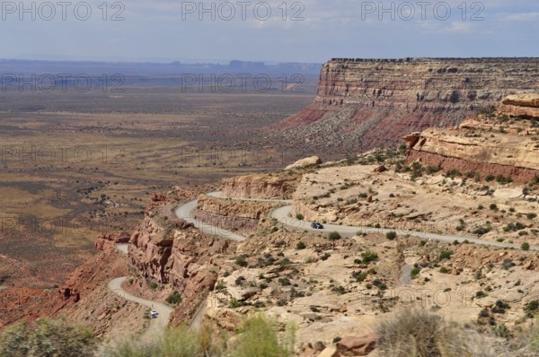 Serpentine road snakes through a rocky desert landscape with sweeping views, Monument Valley, Navajo Tribal Park, Navajo Nation Reservation, Utah, Arizona, USA