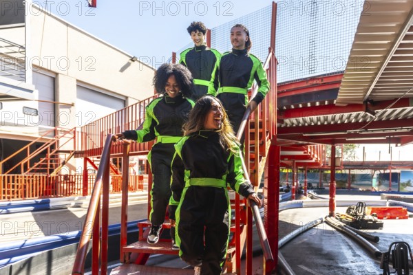 Group of diverse friends wearing racing suits and feeling excited, walking down stairs together at an outdoor go kart track, anticipating a fun competition