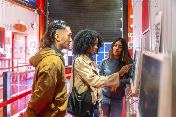 Diverse friends interacting with a digital touchscreen display, selecting racing karts for a fun activity at an indoor karting track, enjoying leisure time and entertainment together