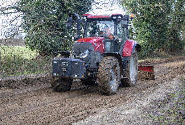 Tractor grading and levelling work repair a muddy, flood-prone country lane, Sutton, Suffolk Sandlings, Suffolk, England, UK