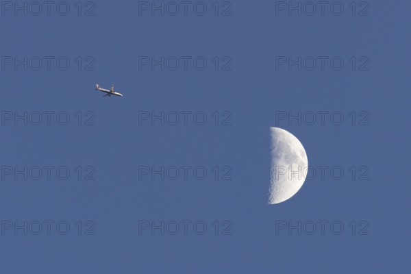 Airbus commercial passenger airliner jet aircraft of British airways in flight with the moon in the background, England, United Kingdom