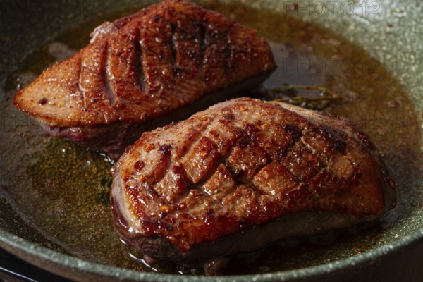 Cooking duck breast, in a frying pan, fried, with spices and herbs, close-up, no people