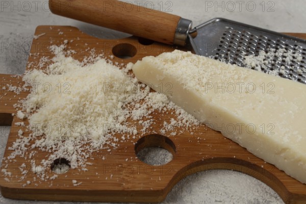 Freshly sliced and grated cheese, parmesan cheese, Gran gusto. Grana padano. on a wooden chopping board, rustic style, no people