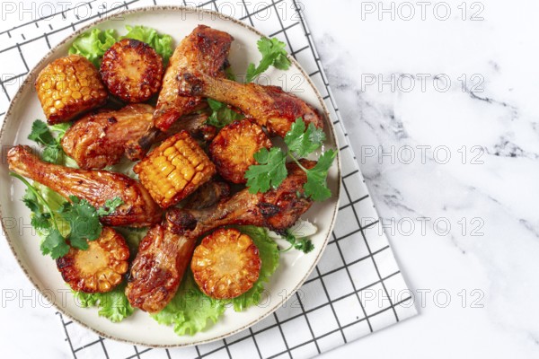 Fried chicken drumsticks, Mexican style, with corn, on a plate, close-up