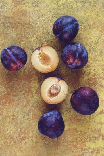 Plums scattered on the table, fresh, top view, yellow-orange background, no people