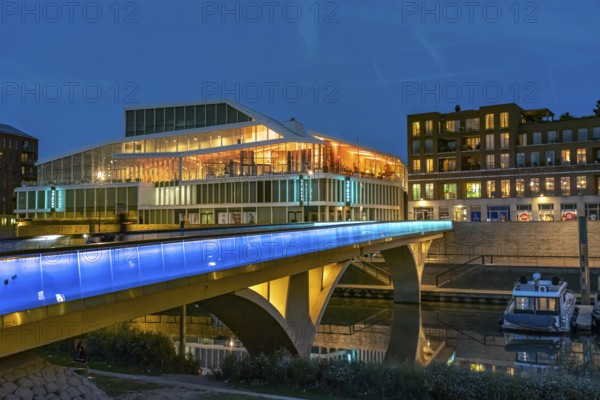 Primark on Maasboulevard and illuminated bridge across the city harbor in Venlo at dusk, the Netherlands