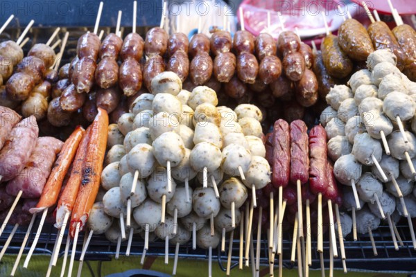 A selection of grilled pork meat sausages including Sai Krok Isan and Moo Ping, satay style meat on a stick a popular Thai street food sold from stalls and markets in Bangkok, Thailand