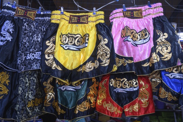 Mae Klong, Thailand. March 15th 2025. Muay Thai martial arts boxing shorts for sale as tourist souvenirs at the Mae Klong Railway market, in Samut Songkhram province of Thailand