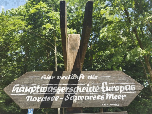 Wooden sign with the inscription Watershed North Sea, Black Sea, in an area surrounded by trees, Franconian mountain trail, hiking in the Fichtelgebirge nature park Park
