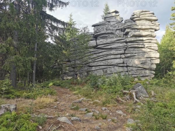 Large rock formations surrounded by trees and vegetation in a forest, Franconian mountain trail, hiking in the Fichtelgebirge nature park Park