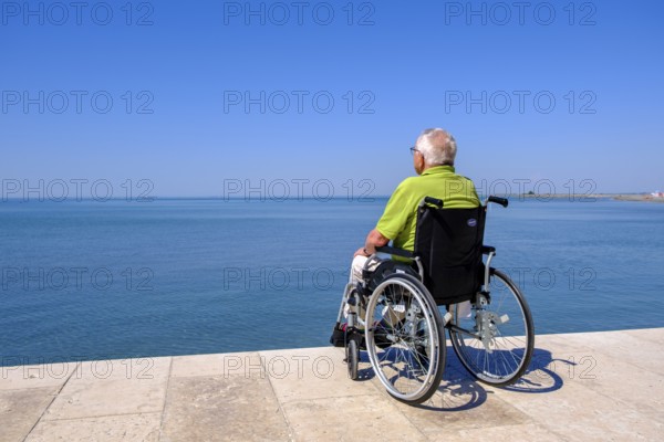 Senior in wheelchair looking at the sea, vacation with a handicap, Grado, Julian-Friuli, Adriatic Sea, Italy