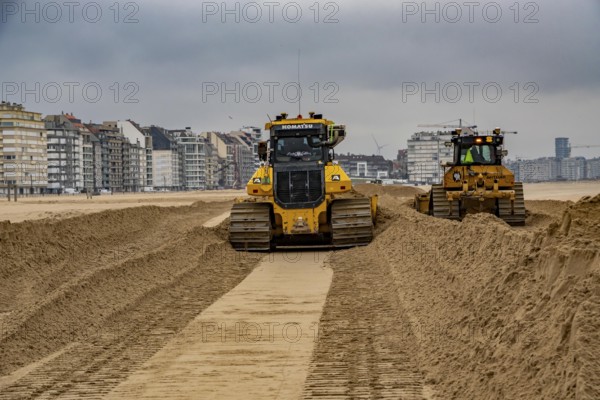 Bulldozers when distributing sand on the beach in the town of Knokke-Heist, part of coastal protection and beach maintenance, due to floods, erosion and sea level rise, the sand on the beach is repeatedly washed into the sea, in winter the sand from the seabed is washed back onto the beach with suction vessels, the excavators and levelers then distribute the sand back on the beach to eliminate the difference in height so as to bathe To make the beach usable again for the next season