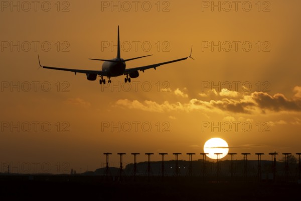 Boeing 737 commercial passenger airliner jet aircraft of Ryanair airways in flight on approach to land over runway lights at sunset at London Stansted airport, Essex, England, United Kingdom