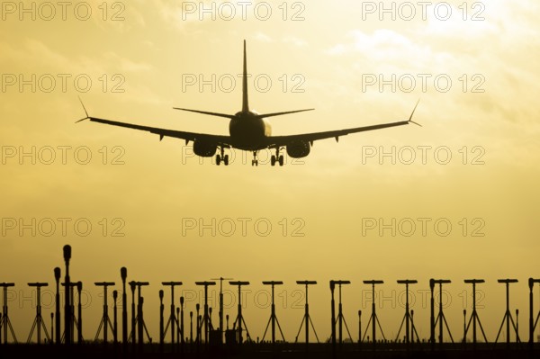 Boeing 737 commercial passenger airliner jet aircraft in flight on approach to land over runway lights at sunset at London Stansted airport, Essex, England, United Kingdom