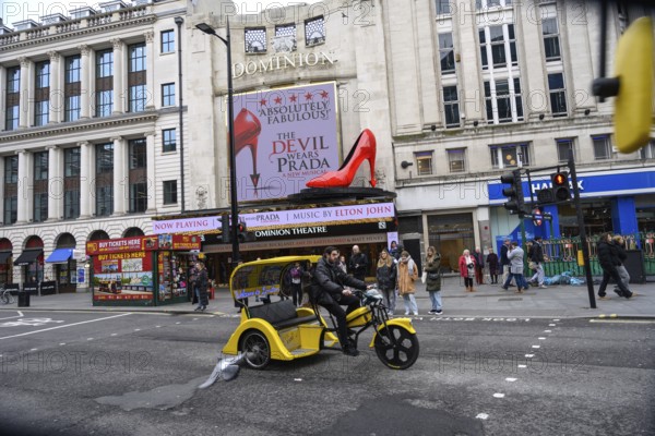 London, UK. January 30th 2025. A yellow tricycle passes the The Dominion Theatre showing The Devil Wears Prada, a musical based on the blockbuster film and bestselling novel, in the West End of London, UK