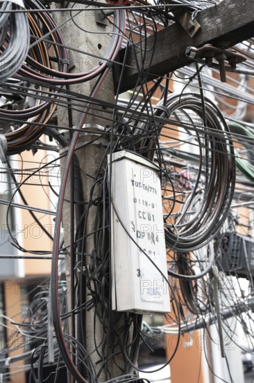 Bangkok, Thailand. March 4th 2025. A tangled mess of cables and wires used for phone and internet connections hanging from a pole in the street in central Bangkok, Thailand