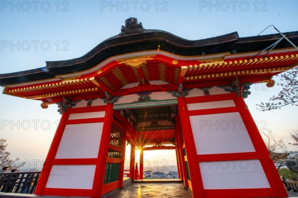 Sunset over the city with sun stars, view through the red Nishimon Gate, Kiyomizu-dera Temple, in the evening light, Buddhist temple complex, Higashiyama, Kyoto
