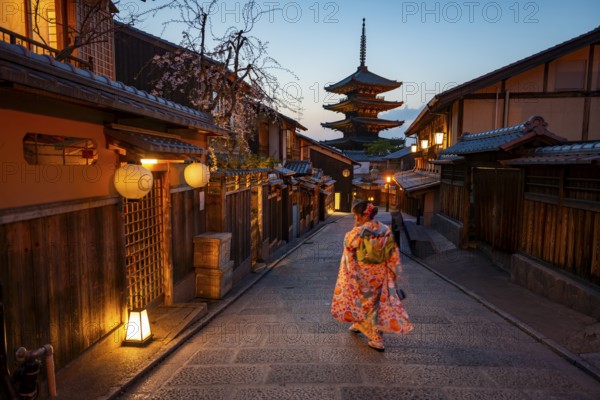 Japanese woman wearing kimono in an alley, Yasaka dori historic alleyway in the old town with traditional Japanese houses, five-story Yasaka pagoda of the Buddhist Hokanji Temple in the back, Higashiyama, Kyoto, Japan