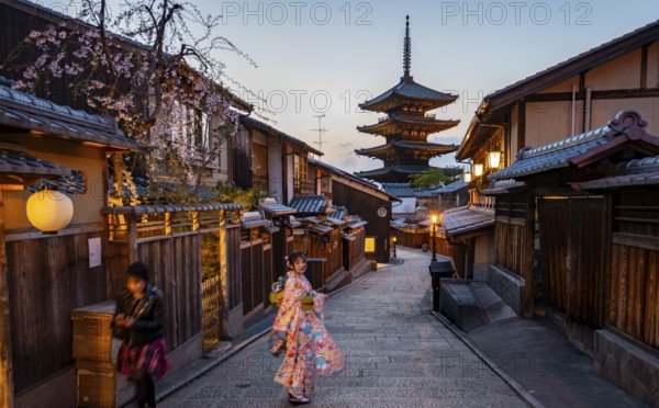 Japanese woman in kimono in an alley, Yasaka dori historic alleyway in the old town with traditional Japanese houses, five-story Yasaka pagoda of the Buddhist Hokanji temple, evening mood, Kyoto, Japan