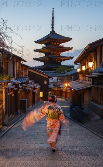 Japanese woman wearing kimono in an alley, Yasaka dori historic alleyway in the old town with traditional Japanese houses, five-story Yasaka pagoda of the Buddhist Hokanji Temple in the back, Higashiyama, Kyoto, Japan