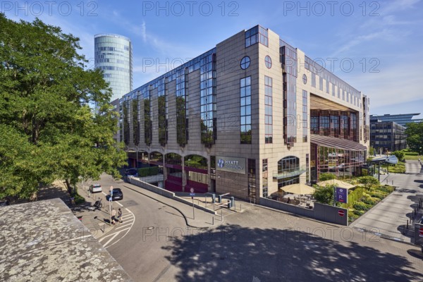 Hyatt Regency, hotel, commercial building, modern architecture, general development, parking strip with cars, flower bed, lawn, trees, elevated perspective, blue sky, cirrus clouds, cirrostratus clouds, Kennedy shore, Cologne, district-free city, North Rhine-Westphalia, Germany