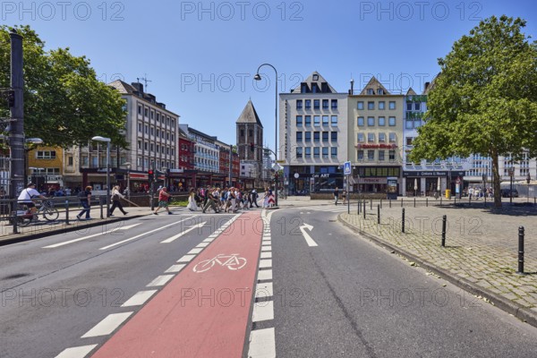 Row of houses, general architecture, houses, lantern, barrier bollard, sidewalk, pedestrian crossing, cycle path, street, traffic lights, road markings lanes, cycle path and directional arrows, pedestrians as accessories, trees, blue sky, cloudless, intersection of Deutz Bridge, Augustinerstraße and Heumarkt, Cologne, district-free city, North Rhine-Westphalia, Germany