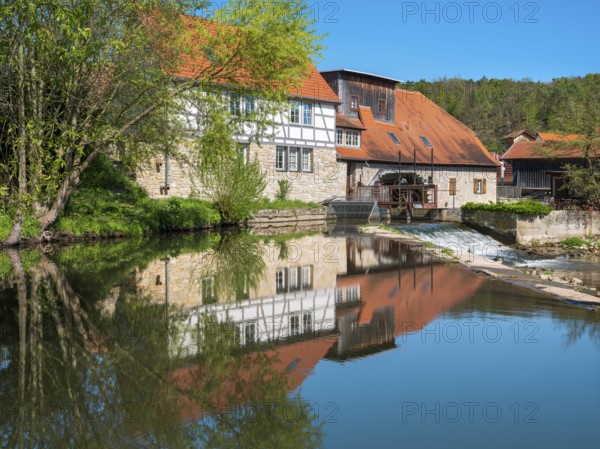The historic water mill is reflected in the river Ilm, Buchfart, Weimarer Land, Thuringia, Germany