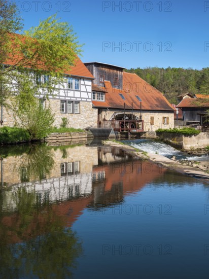 The historic water mill is reflected in the river Ilm, Buchfart, Weimarer Land, Thuringia, Germany