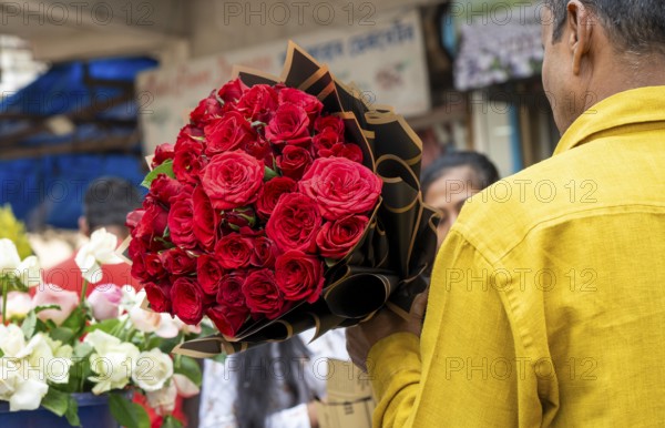 A customer holds a bouquet of red roses at a flower shop on Valentine's Day in Guwahati, India, on 14 February 2026
