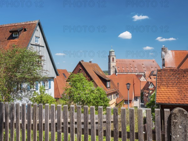 View over wooden fence to the houses in the historic old town and St. Georg Cathedral, on the right a stork nest with white stork, Dinkelsbühl, Ansbach district, Middle Franconia, Bavaria, Germany