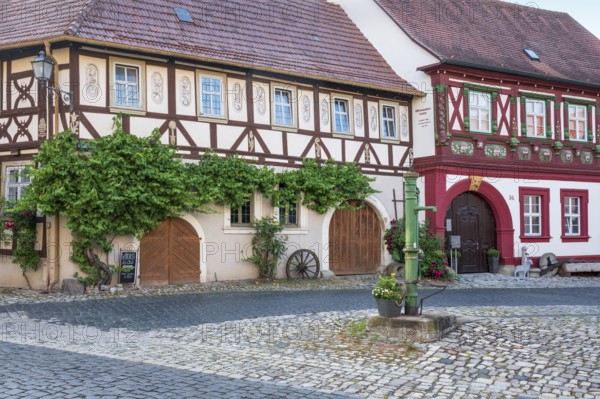 Street in the historic old town with half-timbered houses, cobblestones and hand pump, Alte Schmiede und Uhrmacherhaus, Königsberg in Bavaria, Lower Franconia, Bavaria, Germany