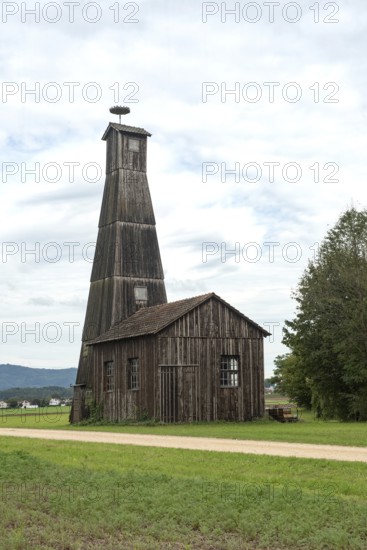 A tall wooden farm building or barn with a storks nest, typical architecture in the Swiss countryside near the city of Basel, Switzerland