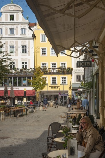 Regensburg, Germany. October 7th 2024 A woman sits at a café in the square of the medieval UNESCO protected city of Regensburg on the River Danube, Germany
