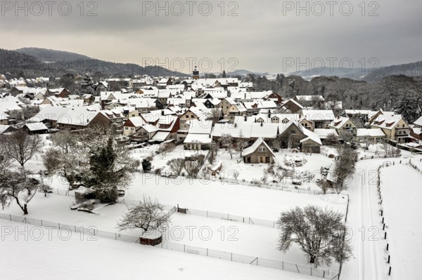 Snowy village with half-timbered houses and gardens under a grey sky, Herleshausen in northern Hesse