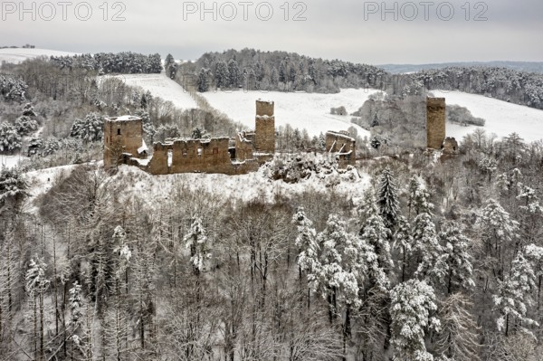 Medieval castle ruins in a snowy hilly landscape with forests, The Brandenburg in the Werra Valley near Eisenach