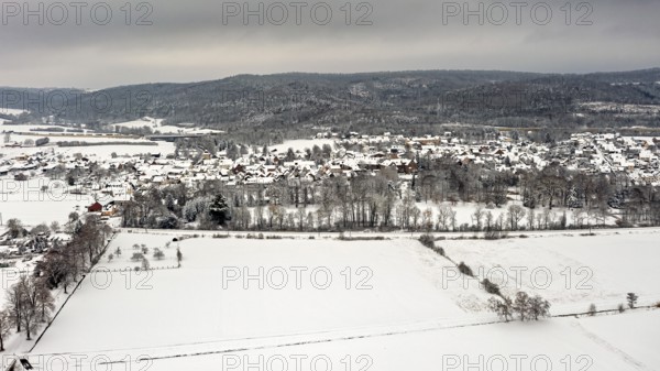 Aerial view of a snowy landscape with fields, hills and a village under grey sky, Herleshausen in northern Hesse